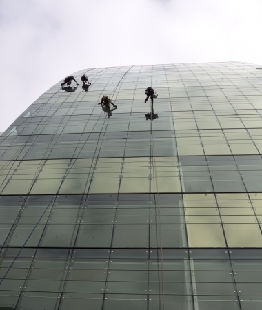 workers risking their lives cleaning skyscraper windowsの写真素材