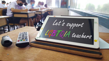 Teaching tools including a tablet, a slide controller and a tv remote are on an aged wooden table, a concept is for lgbtqia teachersâ communities around the worldの写真素材