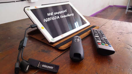 Teaching tools including a tablet, a slide controller and a tv remote are on an aged wooden tableの写真素材