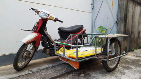 A traditional homemade motorbike with sidecar is parked near a house