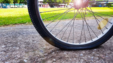An old bike with its reflective badge is parked in a parking area closed to a green field due to the flatten tire, enhanced colors and edited with lens flareの写真素材