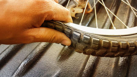 Hand checking the flatten tire on a black floorの写真素材