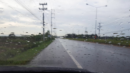 The rainwater drops cover the car window with storm clouds and the evening sunlight in backgroundの写真素材