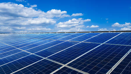 Solar cell panels installed on the roof top of a house with white clouds ,blue sky and the sunlight, to provide power to the house, to go green energy conceptの写真素材