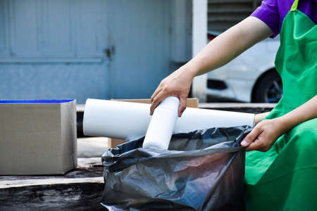 White wastes plastic container sorting into black plastic bag by handの写真素材