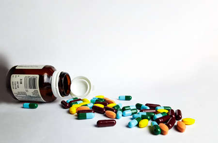 Various medicine pills, orange tablets, blue and green capsules pouring out of the brown bottle, soft and selective focusの写真素材