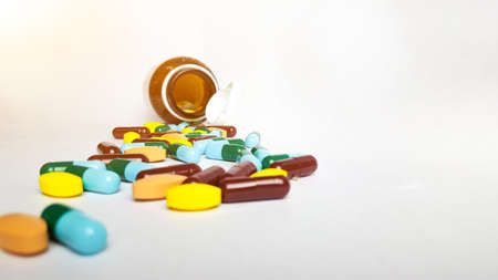 Various medicine pills, orange tablets, blue and green capsules pouring out of the brown bottle, soft and selective focusの写真素材