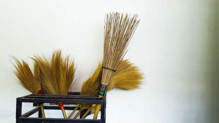 Bà¸ºrooms and coconut broom in the black metal rack close to the white wallの写真素材