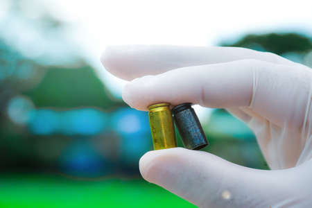 Blur pistol bullet shells holding in white gloved fingersの写真素材