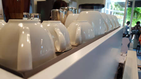 White coffee cups with small reflection of lights  on the white shelf