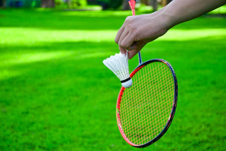 Shuttlecock holding by hand in front of the racket and ready to be servedの写真素材