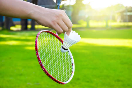 Shuttlecock holding by hand in front of the racket and ready to be servedの写真素材