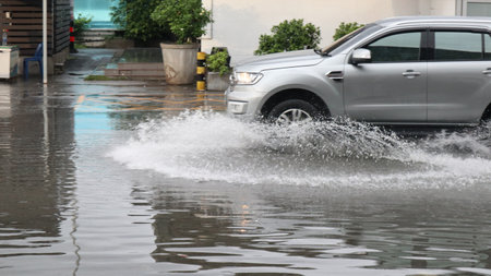 Blur car running and splashing flood water on the flooded street which caused by heavy rain and blocked drainage pipesの写真素材