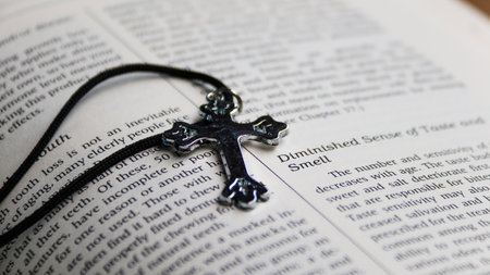 Close up of a Christian cross on an open bible with shallow depth of fieldの写真素材