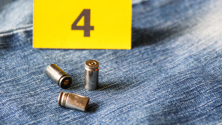 Pistol bullet shells on blur blue jeans and number four display in background, concept for criminal and investigation. soft focusの写真素材