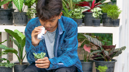 Young boy is using a white small microscope to inspect and to study plant in a tiny flowerpot in botanical garden, soft and selective focusの写真素材