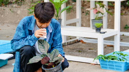 Young boy is using a white small microscope to inspect and to study plant in a tiny flowerpot in botanical garden, soft and selective focusの写真素材