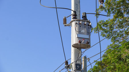 Gray power transformer installed on concrete pole blurred tree and blue sky backgroundの写真素材