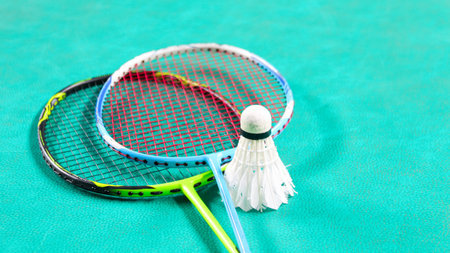 White badminton shuttlecocks and badminton rackets on green floor indoor badminton courtの写真素材