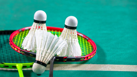 White badminton shuttlecocks and badminton rackets on green floor indoor badminton courtの写真素材