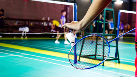 The badminton player holding a white shuttlecock and racket and standing at the net ready to serve.の写真素材