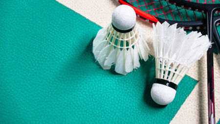 White badminton shuttlecocks and badminton rackets on green floor indoor badminton courtの写真素材