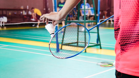 The badminton player holding a white shuttlecock and racket and standing at the net ready to serve.の写真素材