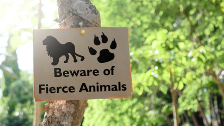 Illustrated with a black lion and a black tiger paw print, the paper sign prominently displays the words Beware of fierce Animals, alerting everyone to the potential danger.の写真素材