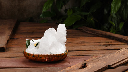 A basket filled with white alum crystals sits on a vibrant green shrub background. The contrasting colors highlight the purity of the alum against the lush greenery, creating fresh feeling.の写真素材