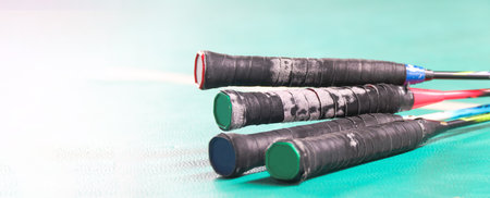 Close up badminton rackets handles on green floor in indoor badminton courtの写真素材