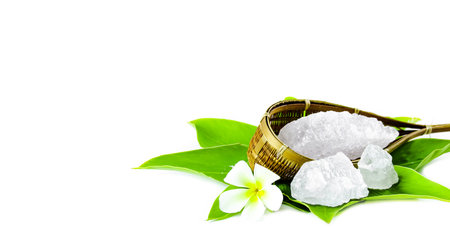 White crystal clear alum cube on green leaf isolated on white background. The chemical compound substance concept of spa and beauty industry.の写真素材