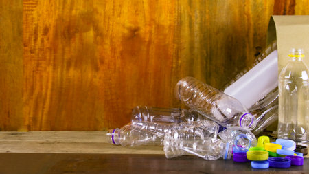 Clear plastic bottles on a wooden surface awaiting recycling. Promotes the concept of recycling waste saving the Earth and conserving natural resources.の写真素材