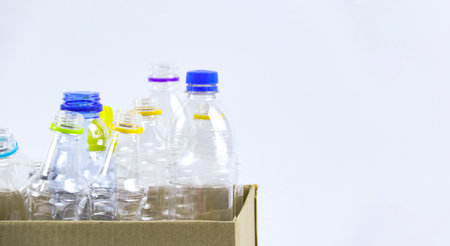 Clear plastic bottles on a white surface, awaiting recycling. Highlights the importance of recycling waste, loving the Earth, and conserving natural resources.の写真素材