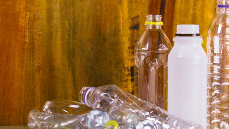 Clear plastic bottles on a wooden surface awaiting recycling. Promotes the concept of recycling waste saving the Earth and conserving natural resources.の写真素材
