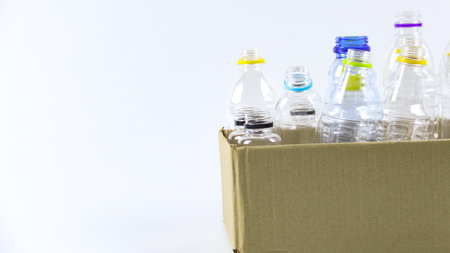 Clear plastic bottles on a white surface, awaiting recycling. Highlights the importance of recycling waste, loving the Earth, and conserving natural resources.の写真素材