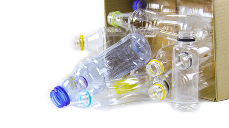 Clear plastic bottles on a white surface, awaiting recycling. Highlights the importance of recycling waste, loving the Earth, and conserving natural resources.の写真素材