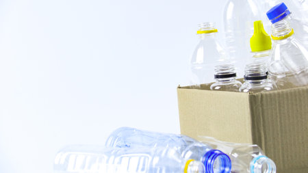 Clear plastic bottles on a white surface, awaiting recycling. Highlights the importance of recycling waste, loving the Earth, and conserving natural resources.の写真素材