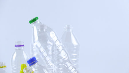 Clear plastic bottles on a white surface, awaiting recycling. Highlights the importance of recycling waste, loving the Earth, and conserving natural resources.の写真素材