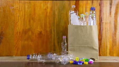 Clear plastic bottles on a wooden surface awaiting recycling. Promotes the concept of recycling waste saving the Earth and conserving natural resources.の写真素材