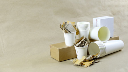 White paper coffee cup, used paper, and cardboard box on a brown surface, awaiting recycling. Promotes recycling waste, saving the Earth, and conserving natural resources.の写真素材