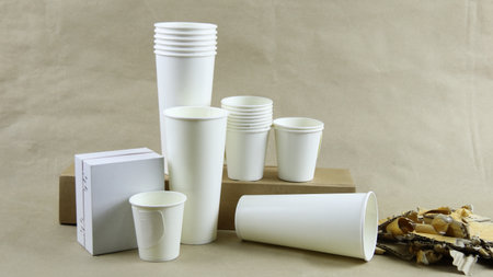 White paper coffee cup, used paper, and cardboard box on a brown surface, awaiting recycling. Promotes recycling waste, saving the Earth, and conserving natural resources.の写真素材