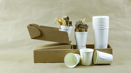 White paper coffee cup, used paper, and cardboard box on a brown surface, awaiting recycling. Promotes recycling waste, saving the Earth, and conserving natural resources.の写真素材