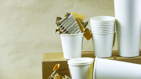 White paper coffee cup, used paper, and cardboard box on a brown surface, awaiting recycling. Promotes recycling waste, saving the Earth, and conserving natural resources.の写真素材