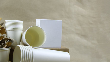 White paper coffee cup, used paper, and cardboard box on a brown surface, awaiting recycling. Promotes recycling waste, saving the Earth, and conserving natural resources.の写真素材