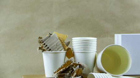 White paper coffee cup, used paper, and cardboard box on a brown surface, awaiting recycling. Promotes recycling waste, saving the Earth, and conserving natural resources.の写真素材