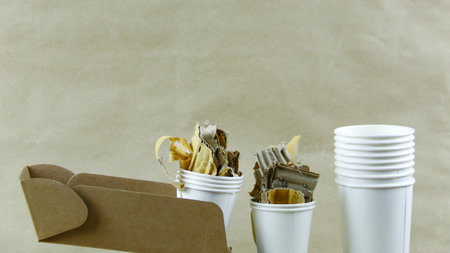 White paper coffee cup, used paper, and cardboard box on a brown surface, awaiting recycling. Promotes recycling waste, saving the Earth, and conserving natural resources.の写真素材