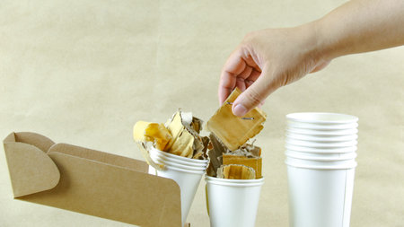 White paper coffee cup, used paper, and cardboard box on a brown surface, awaiting recycling. Promotes recycling waste, saving the Earth, and conserving natural resources.の写真素材