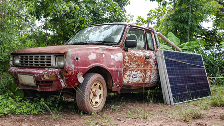 Image of a rusty vintage pickup truck with solar panels leaning against it. This showcases the blend of classic automotive design with modern renewable energy solutions.の写真素材