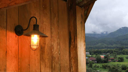 Image of an antique lamp covered in dust and cobwebs, mounted on an old dark brown wooden plank wall in old antique houseの写真素材