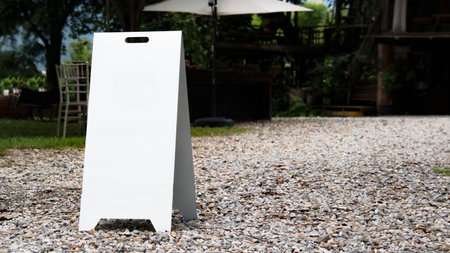 A blank white signboard standing on a gravel-paved surface, offering ample space for customized text or branding.の写真素材